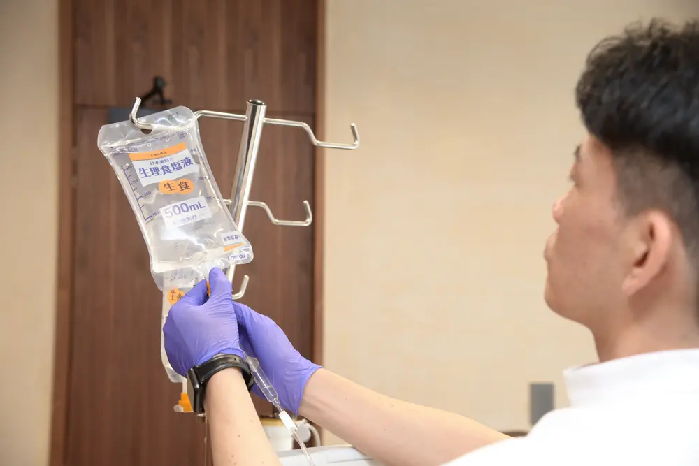 A member of our staff setting a bag of saline on the stand before treatment
